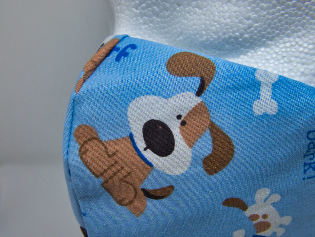 close photo of facemask made of cartoon dog on blue background fabric