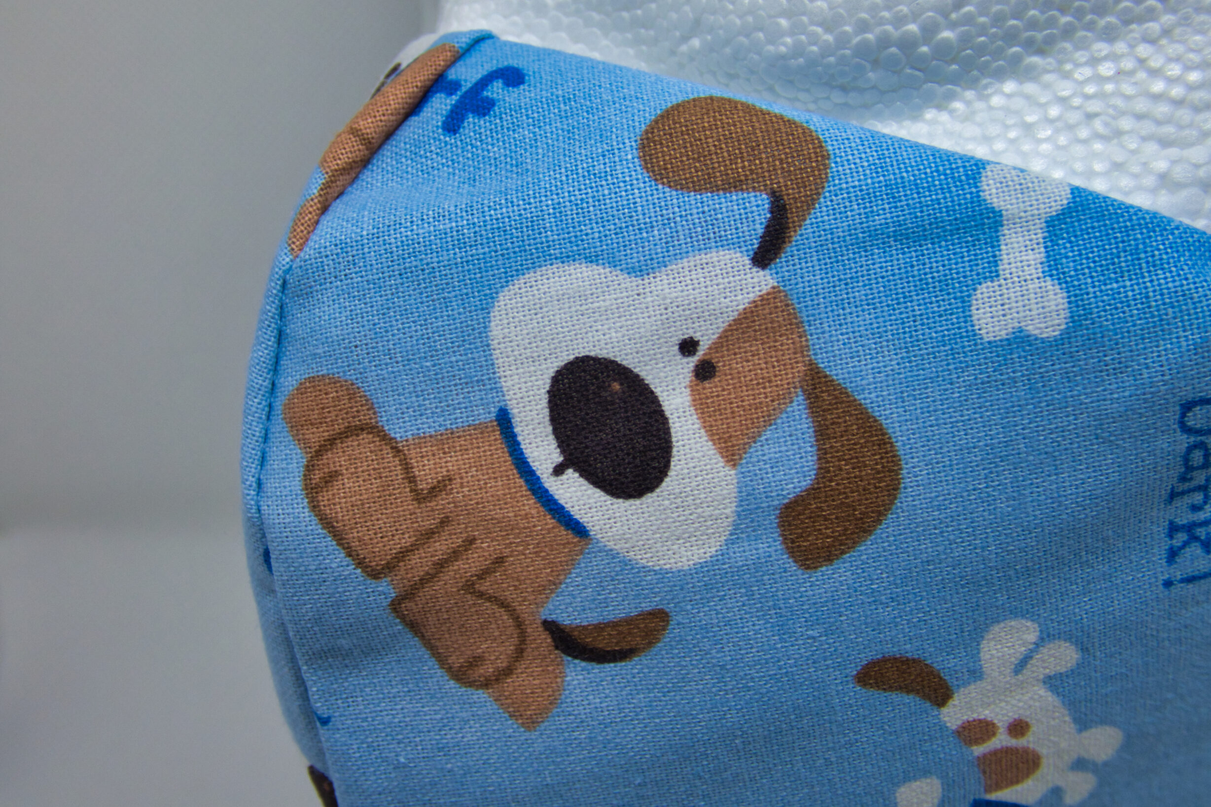 close photo of facemask made of cartoon dog on blue background fabric